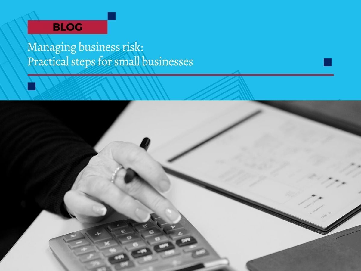Close-up of a person using a calculator with business notes on a desk, overlaid with blog title ‘Managing business risk: Practical steps for small businesses’.