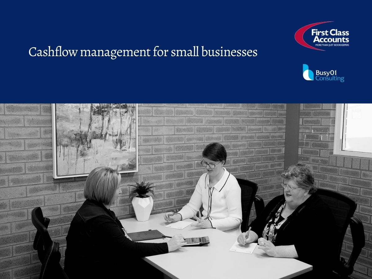 Three women seated at a table in a small business meeting, reviewing paperwork and a calculator during a cashflow management discussion at First Class Accounts Ovens & Murray.
